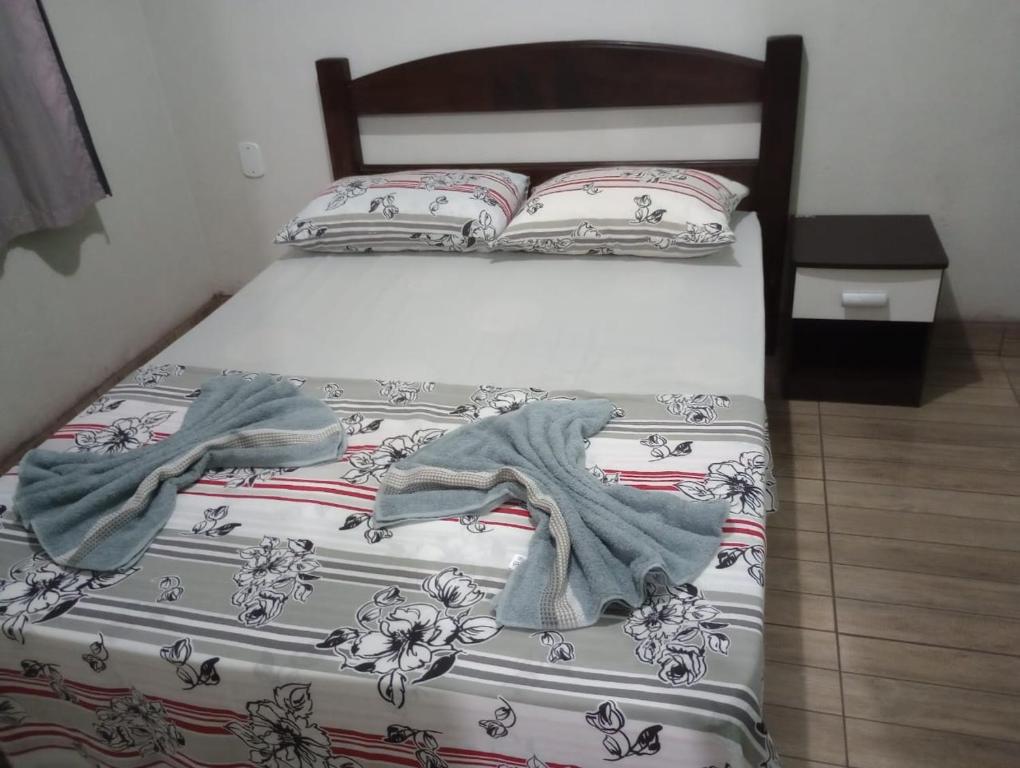 uma cama com dois cobertores e almofadas em Casa Para Temporada - Cantinho da Cida em Serra