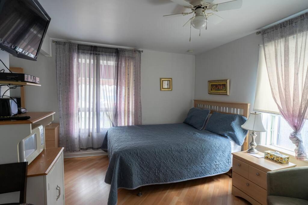 Schlafzimmer mit einem Bett, einem TV und Fenstern in der Unterkunft 307 Chambre Double pour Travailleurs in Trois-Rivières