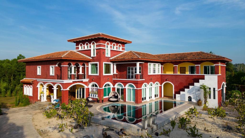 una gran casa roja con una piscina frente a ella en Hacienda Resort - Mae Phim en Mae Pim
