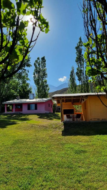 una casa con un campo de hierba delante de ella en Cabañas La Ofelia en Potrerillos
