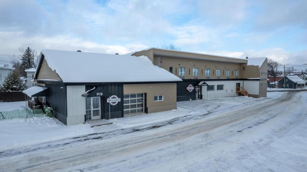 a building on a snow covered street with a building at Hôtel St-Alexis in Saint-Raymond