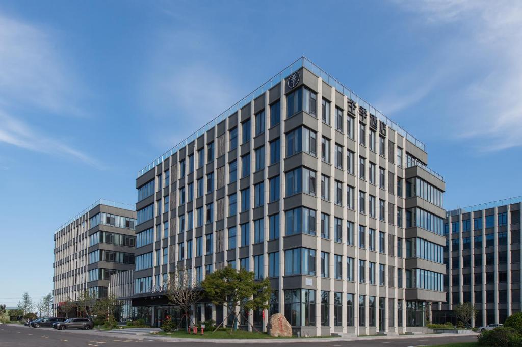 a tall building with many windows on a street at All Seasons Hotel - Jiaozhou Jiaodong Airport Liwang Road in Jiaozhou