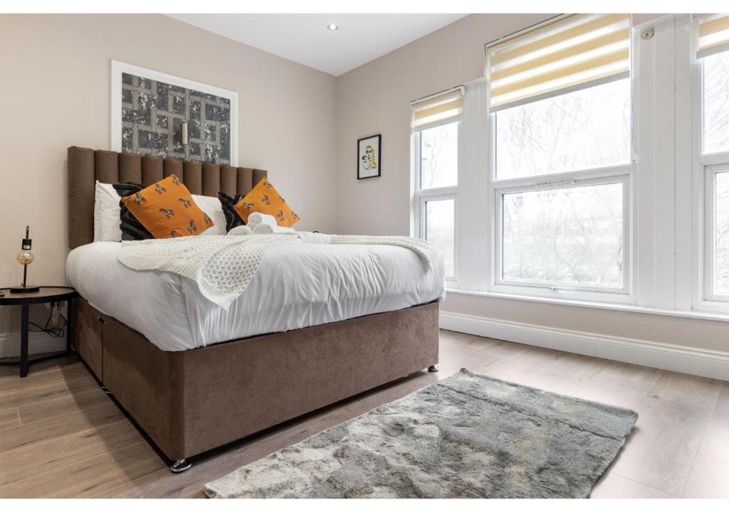 a bedroom with a large bed and two windows at Brand New Homey and Stylish Perfect for Travellers in London