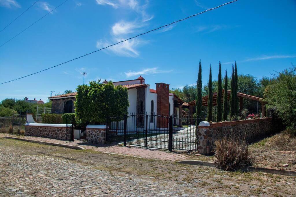 una valla frente a una casa con árboles en Casa rústica de campo, en Tecozautla