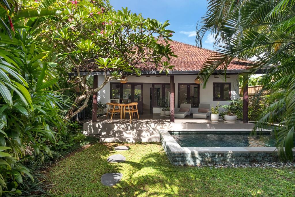 Un patio trasero con piscina y una casa. en Twist and Shout Villa, en Seminyak