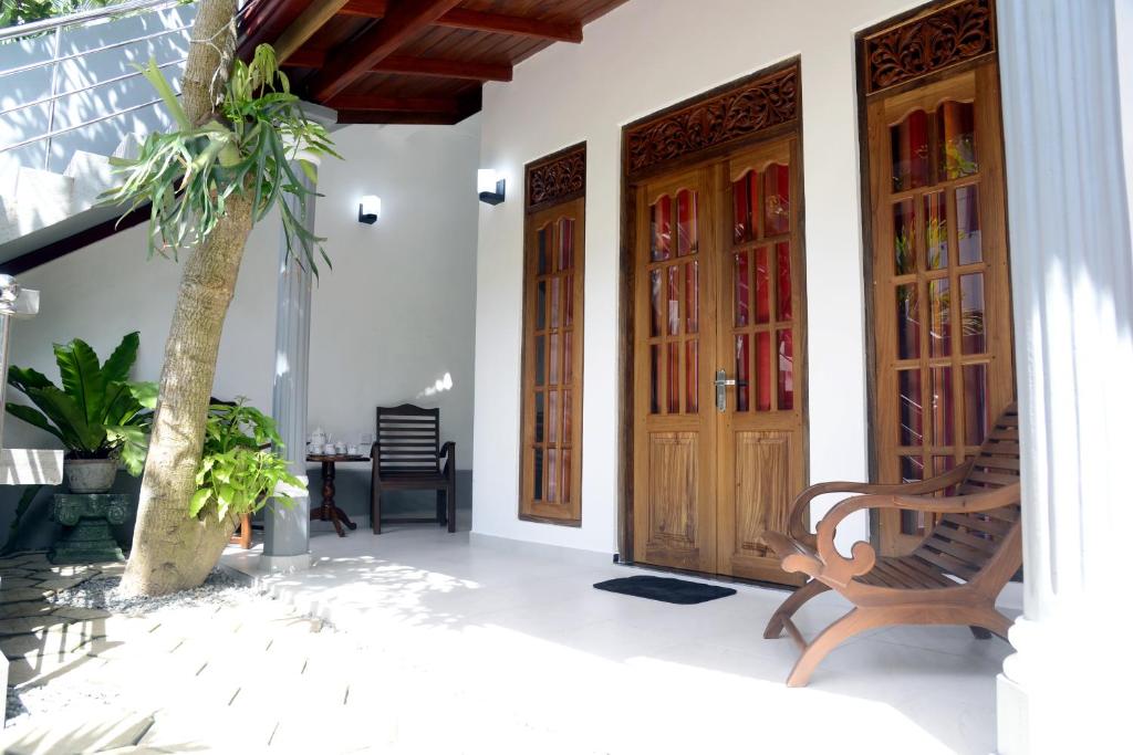 a house with two wooden doors and a palm tree at Aayu's Guest in Bentota