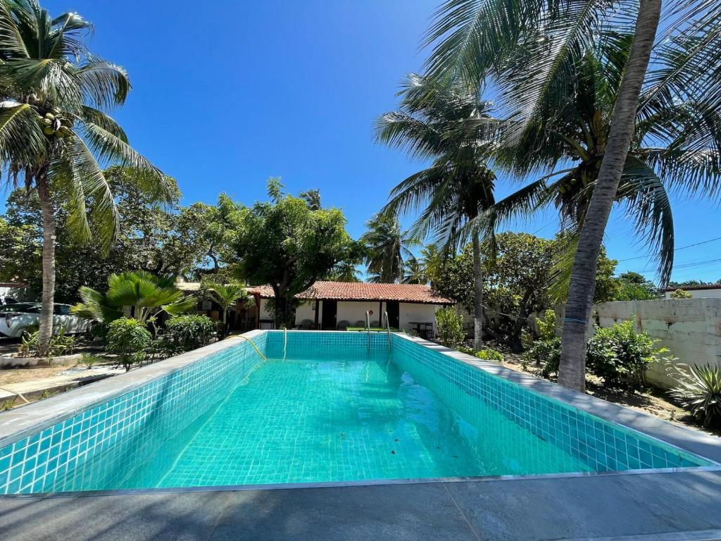 a swimming pool in front of a house with palm trees at Casa Encanto da Barra in Fortim