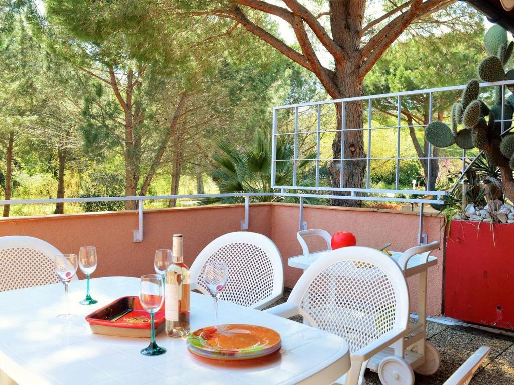 une table blanche et des chaises sur une terrasse dans l'établissement Appartement 3 pièces avec piscine, terrasse et WIFI - Le Lavandou - FR-1-251-561, au Lavandou