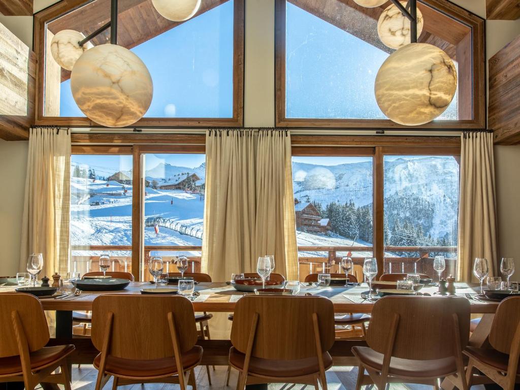 a dining room with a table and chairs and windows at Chalet Penthouse Luxe à Méribel - Concierge, Spa, Parking - FR-1-613-41 in Méribel