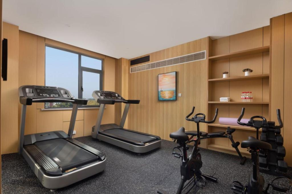 a gym with three treadmills and three exercise bikes at Wanda Yue Suzhou Huangdai in Suzhou