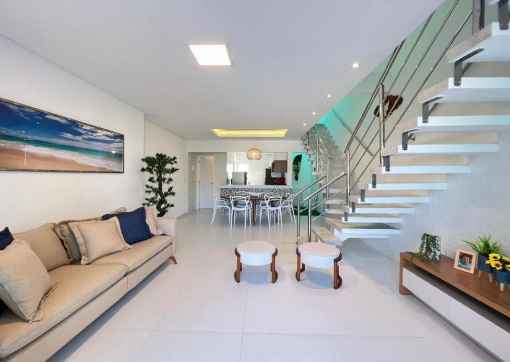 a living room with a couch and a staircase at Bela casa condominio beira mar praia dos carneiros in Tamandaré