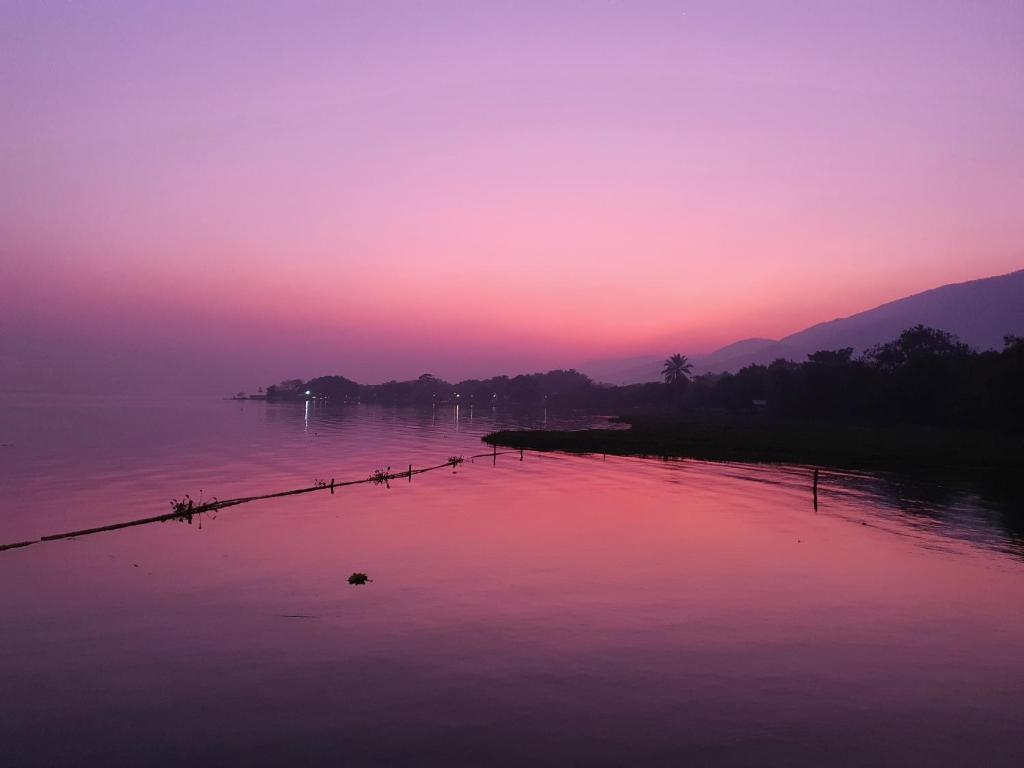 una puesta de sol rosa y morada sobre un cuerpo de agua en Hotel Ecológico Cabañas del Lago, en El Estor