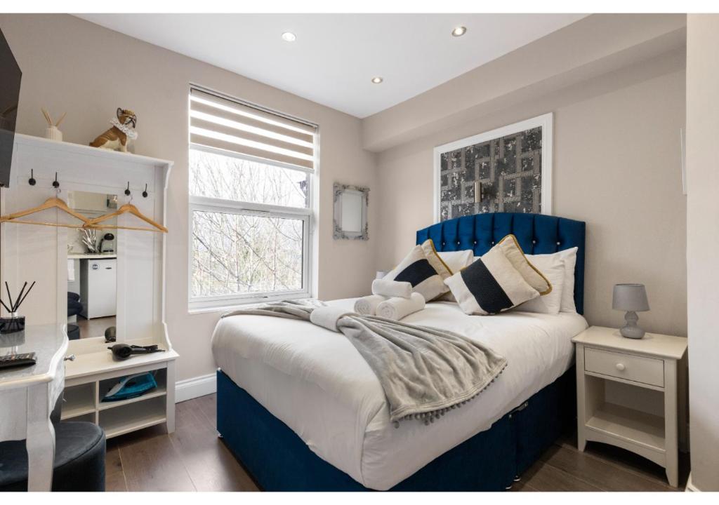 Un dormitorio con una cama azul y blanca y un escritorio en Brand New Stunning and Cosy Studio - Very Central en Londres