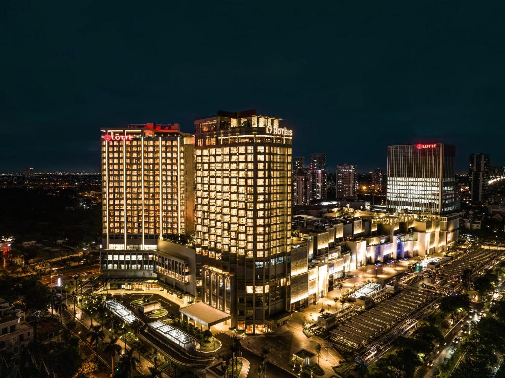 une ville éclairée la nuit avec des bâtiments dans l'établissement L7 WEST LAKE HANOI By LOTTE, à Hanoï