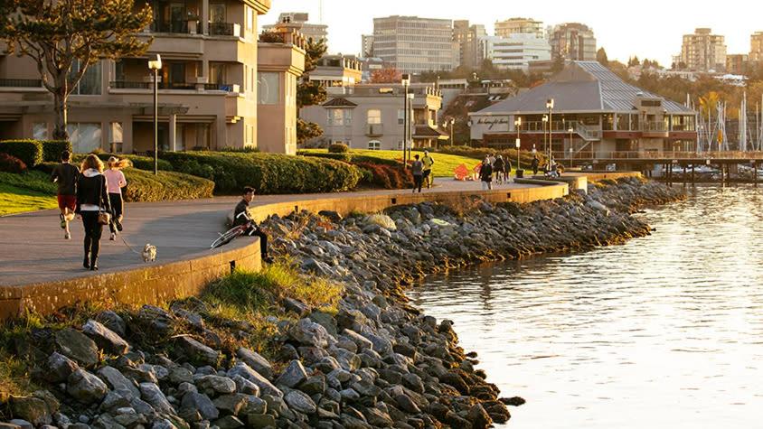 a group of people walking on a sidewalk next to a river at Charming Heritage Home with Mountain and City Views in Vancouver