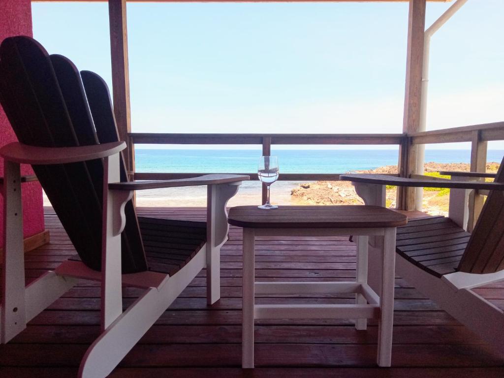 porche con 2 sillas, mesa y vistas a la playa en Casa Corazon Striking Beach Home en Utila