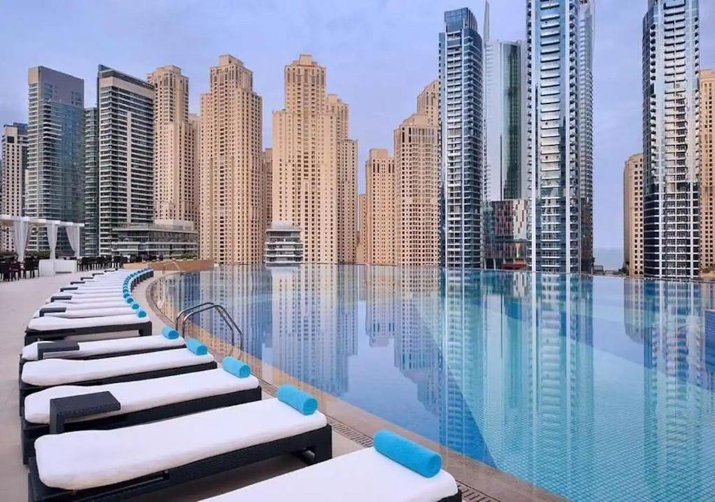 a pool with chaise lounges in front of a city skyline at 5-Star Studio at The Address Marina, Mall Access in Dubai