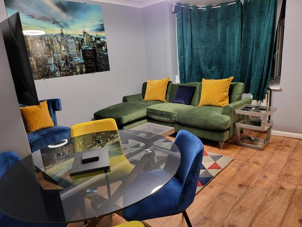 a living room with a glass table and blue chairs at Garland Modern House With Parking & Garden in Borehamwood