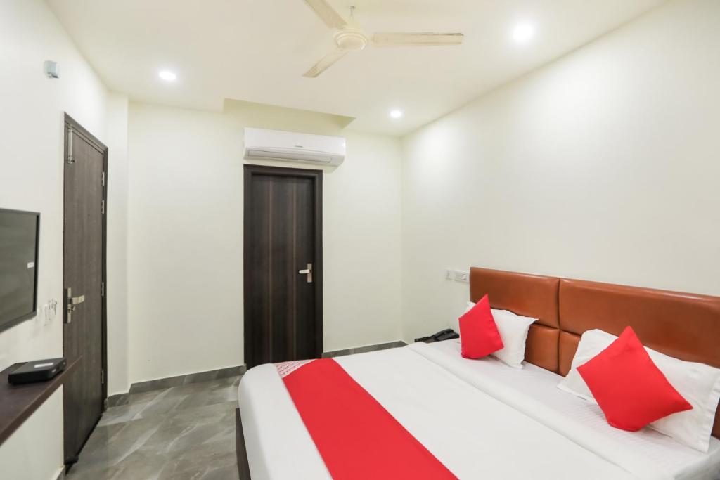 a bedroom with a bed with red and white pillows at Hotel Krishna in Faridabad