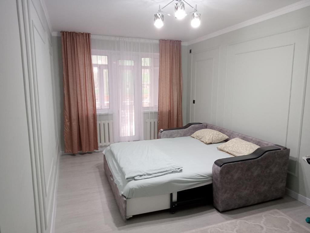 ein Schlafzimmer mit einem Bett in einem Zimmer mit Fenstern in der Unterkunft Orda in Qysylorda