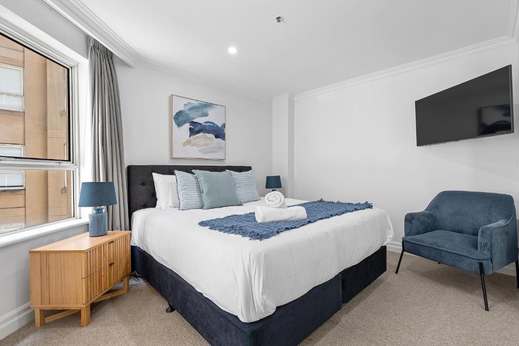 een slaapkamer met een groot bed en een blauwe stoel bij Discover Bond Street in Sydney