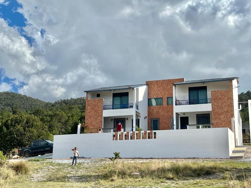 une personne debout devant une maison dans l'établissement Casa De Campo Mirador H&L, à San Antonio de las Alzanas
