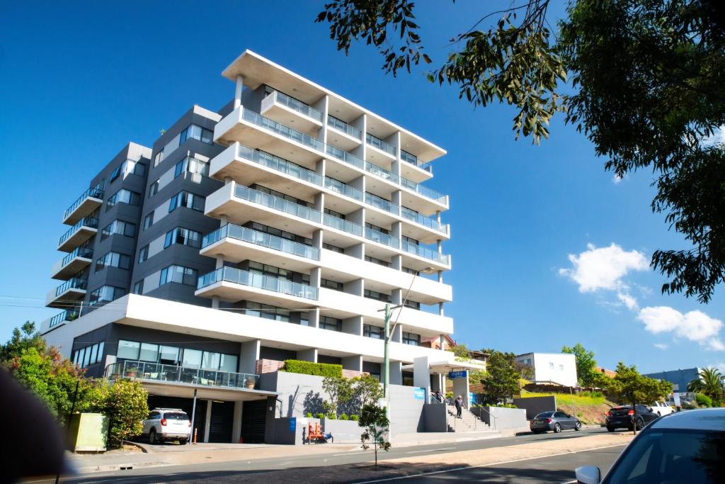 a tall white apartment building on a street at Mantra Wollongong in Wollongong
