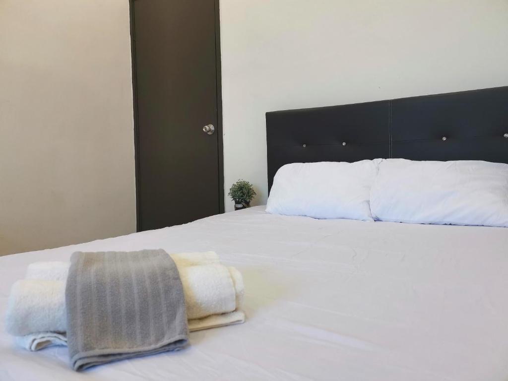 ein Schlafzimmer mit einem weißen Bett und Handtüchern darauf in der Unterkunft Cosy 19 white house@Bukit Mertajam, Alma penang in Bukit Mertajam