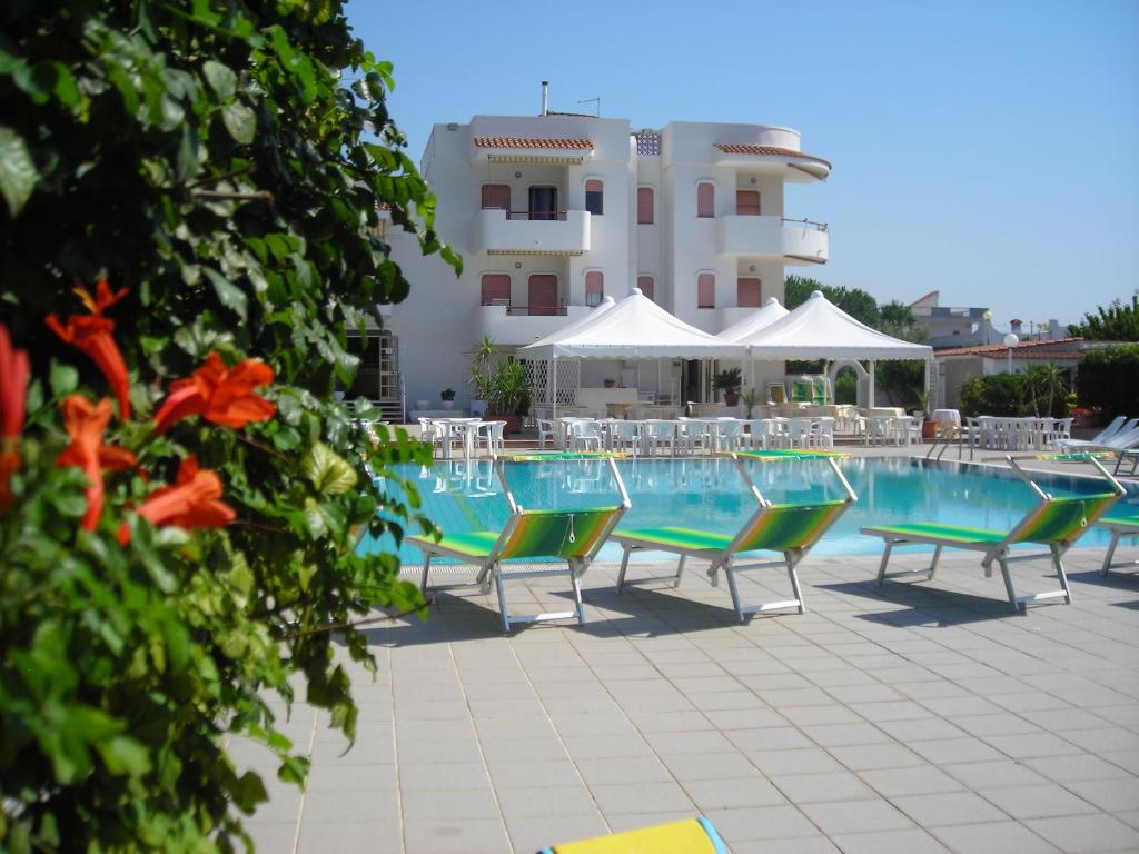 une piscine avec des chaises et un bâtiment en arrière-plan dans l'établissement Residence Atlante, à Leporano