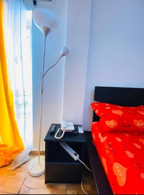 un letto con tavolo, lampada e telecomando di Guesthouse & énergie a Douala