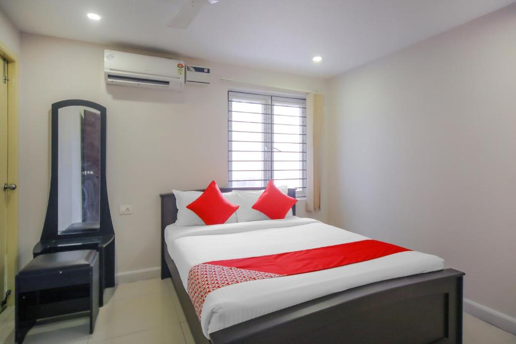 Schlafzimmer mit einem Bett mit roten Kissen und einem TV in der Unterkunft Pride Hospitality Nungambakkam in Chennai
