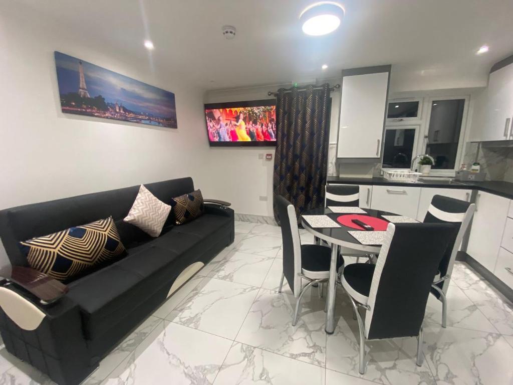 a living room with a black couch and a table at THE ROYAL BOUTIQUE OXFORD LODGE BY LONDON HEATHROW UK, PRIVATE APARTMENT OFFER's FREE PARKING, WIFI , KITCHEN & LAUNDRY SERVICES, SLEEP 8 in Hayes