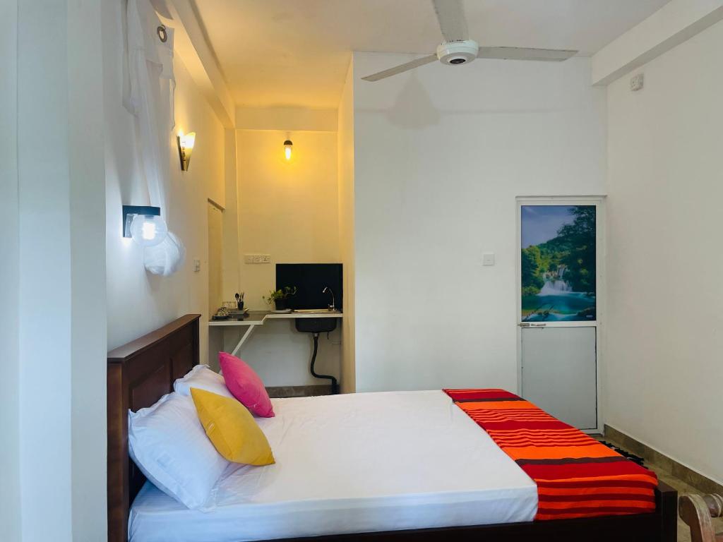 um quarto com uma cama branca e almofadas coloridas em Sri Mali em Matara