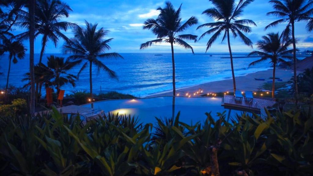 uma vista para o oceano a partir de um resort à noite em Niraamaya Wellness Retreats, Surya Samudra, Kovalam em Kovalam