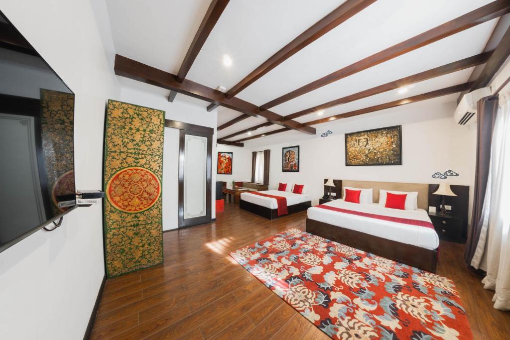 a bedroom with two beds and a flat screen tv at Dalai-La Boutique Hotel in Kathmandu