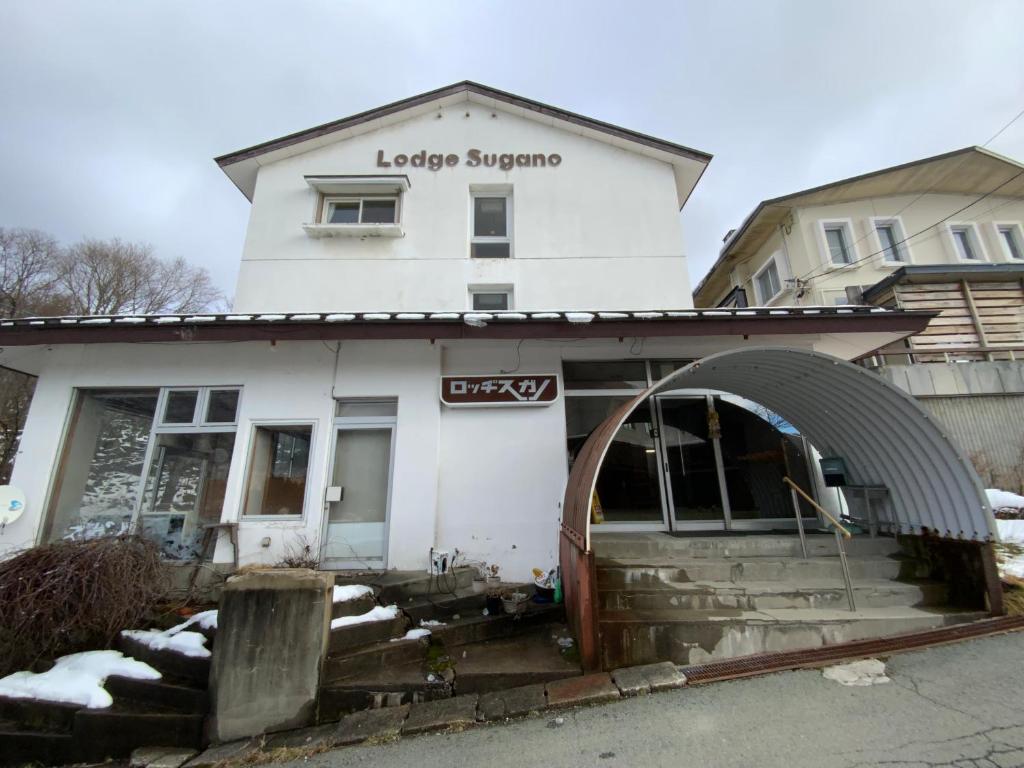 a white building with an archway in front of it at ロッヂ　スガノ in Zaō Onsen