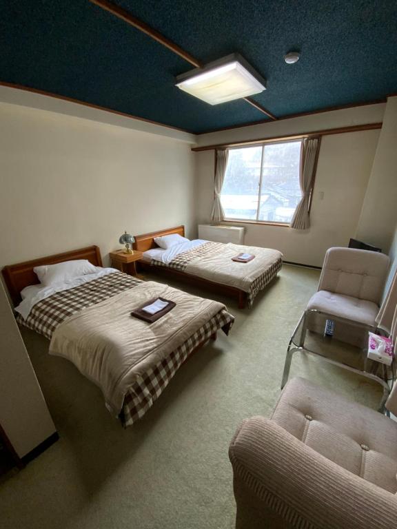 um quarto com 2 camas, uma cadeira e um sofá em ロッヂ　スガノ em Zao Onsen