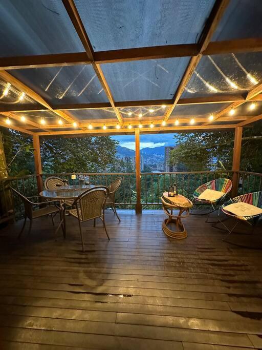 een afgeschermde veranda met een tafel, stoelen en verlichting bij Cabaña sendero verde in Envigado