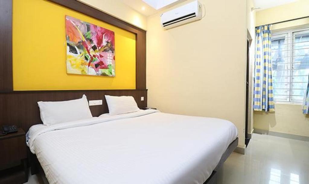 um quarto com uma grande cama branca num quarto em FabHotel Elite Inn em Trivandrum