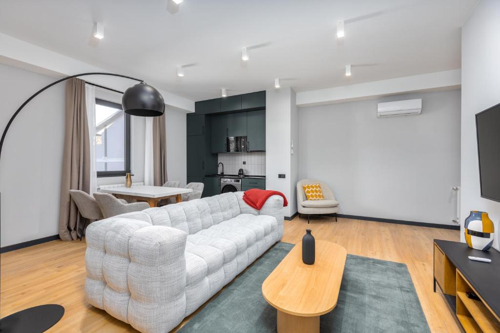 a living room with a white couch and a table at Gratus Aparthotel Tbilisi in Tbilisi City