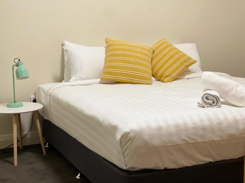a bed with yellow and white pillows and a table at Stylish 4 Bedroom Urban Retreat in Wagga Wagga