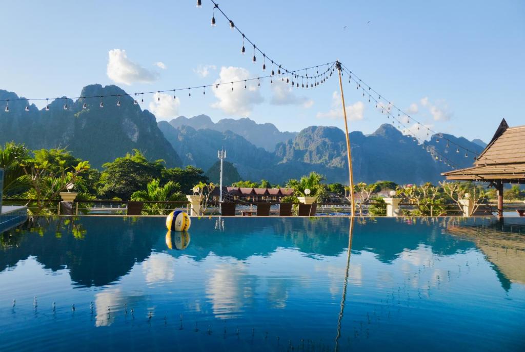 a view of a pool with mountains in the background at Silver Naga Hotel in Vang Vieng