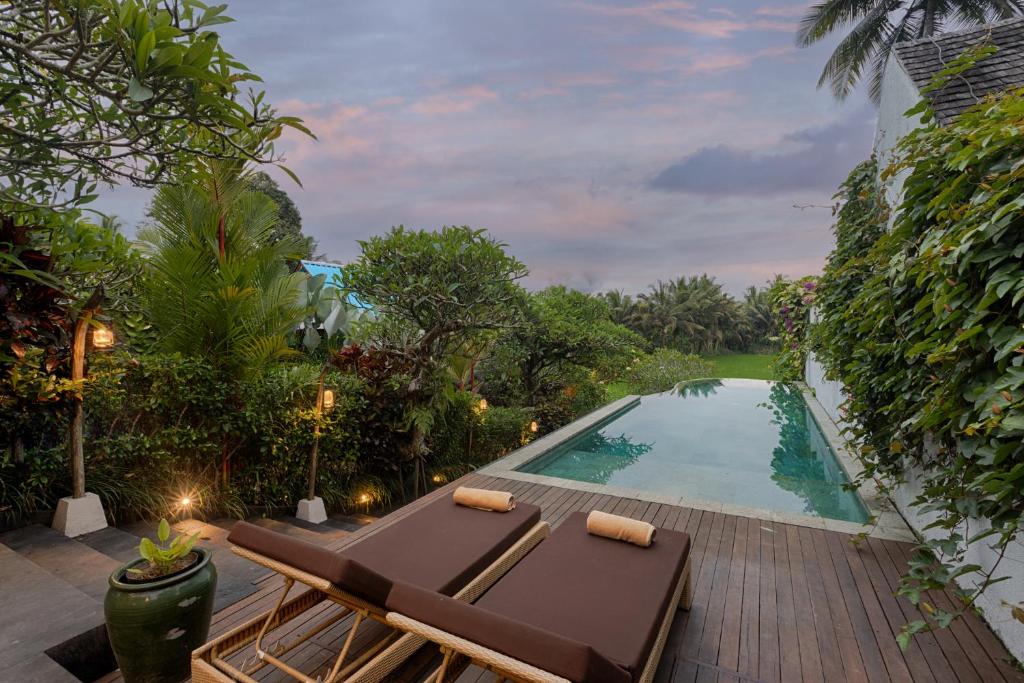 uma piscina com uma chaise longue ao lado de um resort em Ubud Padi Villas em Ubud