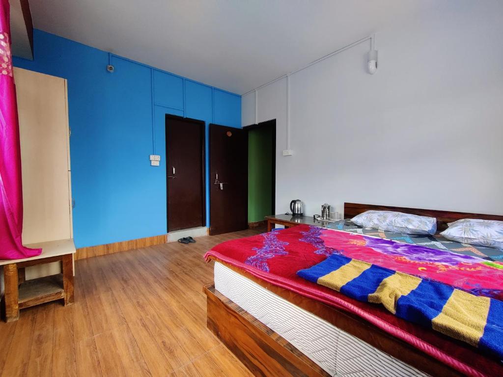 a bedroom with a bed with blue walls and wooden floors at Hotel Paramount in Dentam