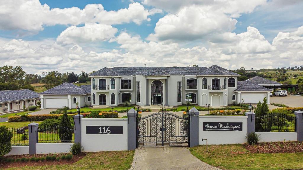 a large white house with a gate at Villa Tasha Luxury Suites, Lanseria in Johannesburg