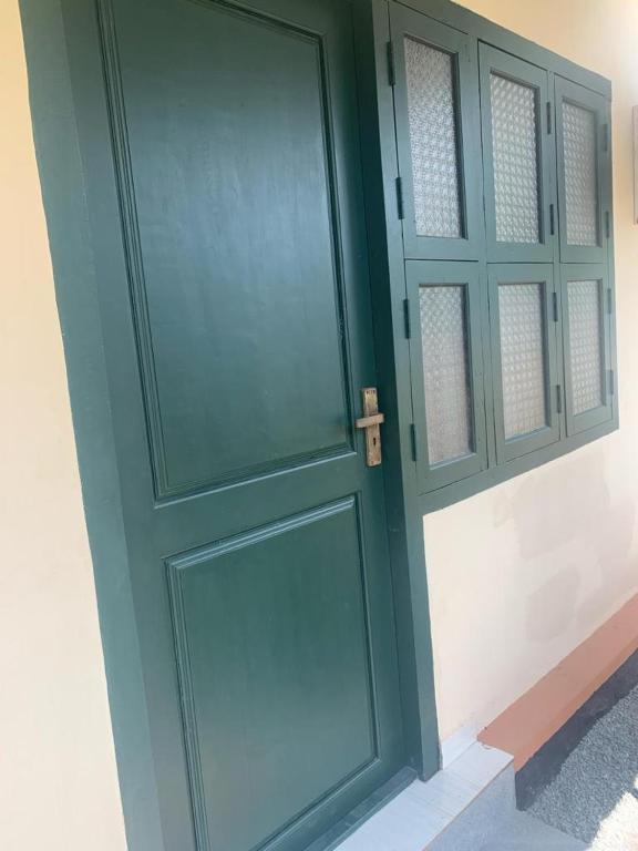 a green door in a room with a white wall at RD's abode in Kozhikode