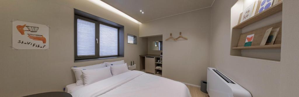 a bedroom with a white bed and a window at Stay Dooroo in Suncheon