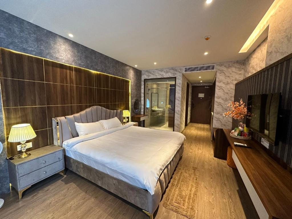 een slaapkamer met een groot bed en een televisie bij Apec Condotel Phan Thiet By Tien Vu in Mũi Né
