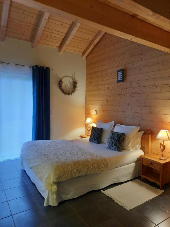 um quarto com uma cama grande e uma parede de madeira em Au Cœur des Lacs - Chambres d'hôtes em Gérardmer