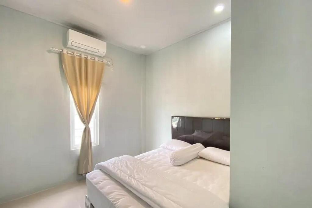 a white bedroom with a bed and a window at RedDoorz Syariah near Kantor Bupati Pantai Pandan Sibolga in Halangan